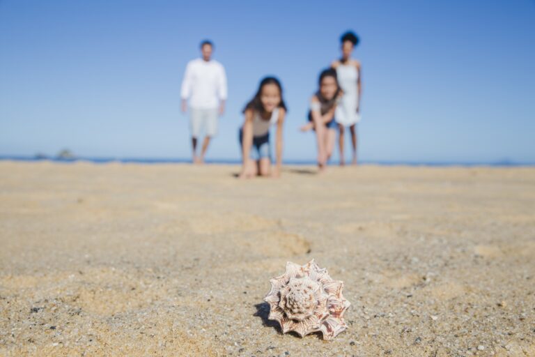 Rodzina ciesząca się plażą w Kołobrzegu z dziećmi bawiącymi się w piasku.